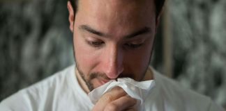 man with tissue and runny nose