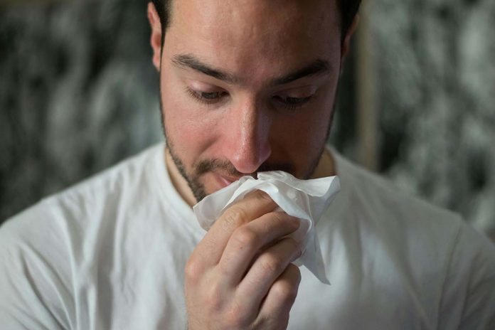 man with tissue and runny nose